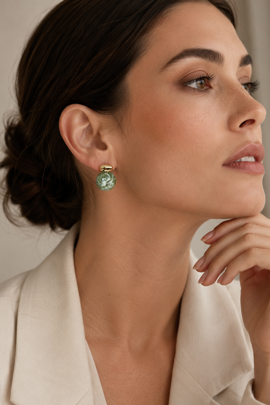 Woman wearing a green earring with a neutral background