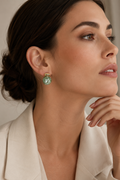 Woman wearing a green earring with a neutral background