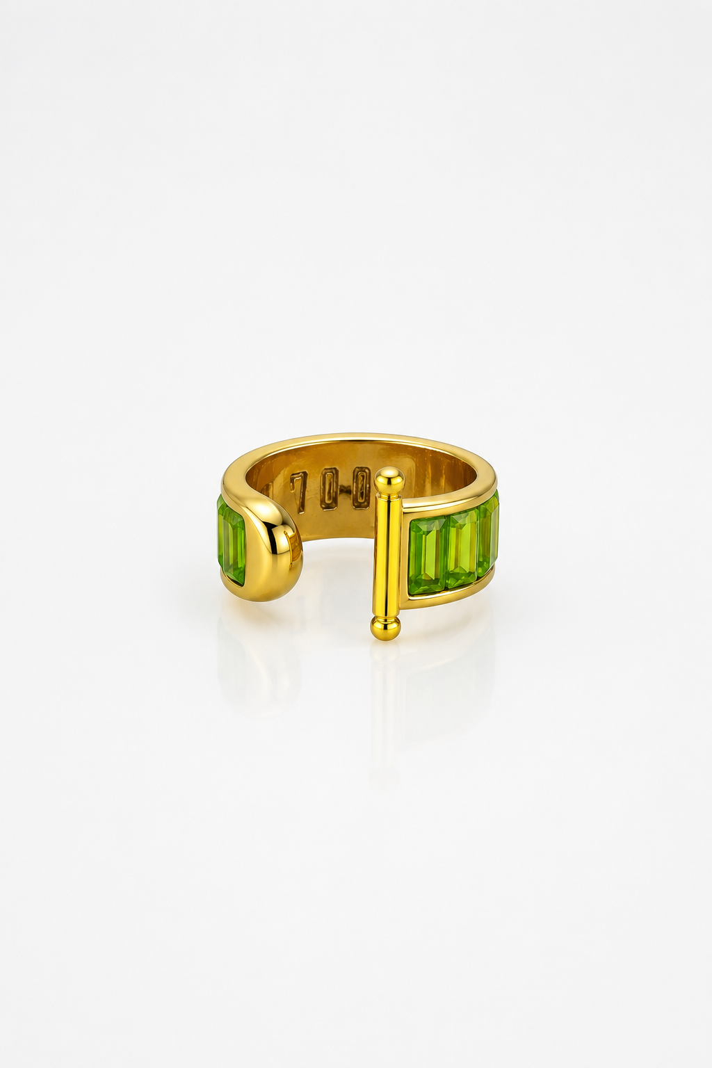 Gold ring with green gemstones on a white background