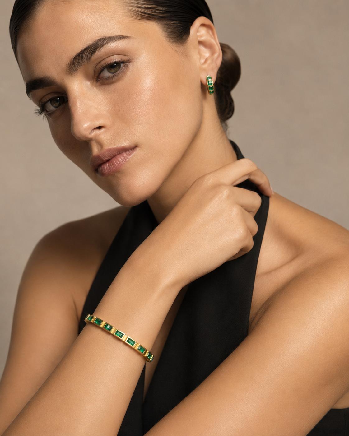 Woman wearing a bracelet and earrings with a neutral background