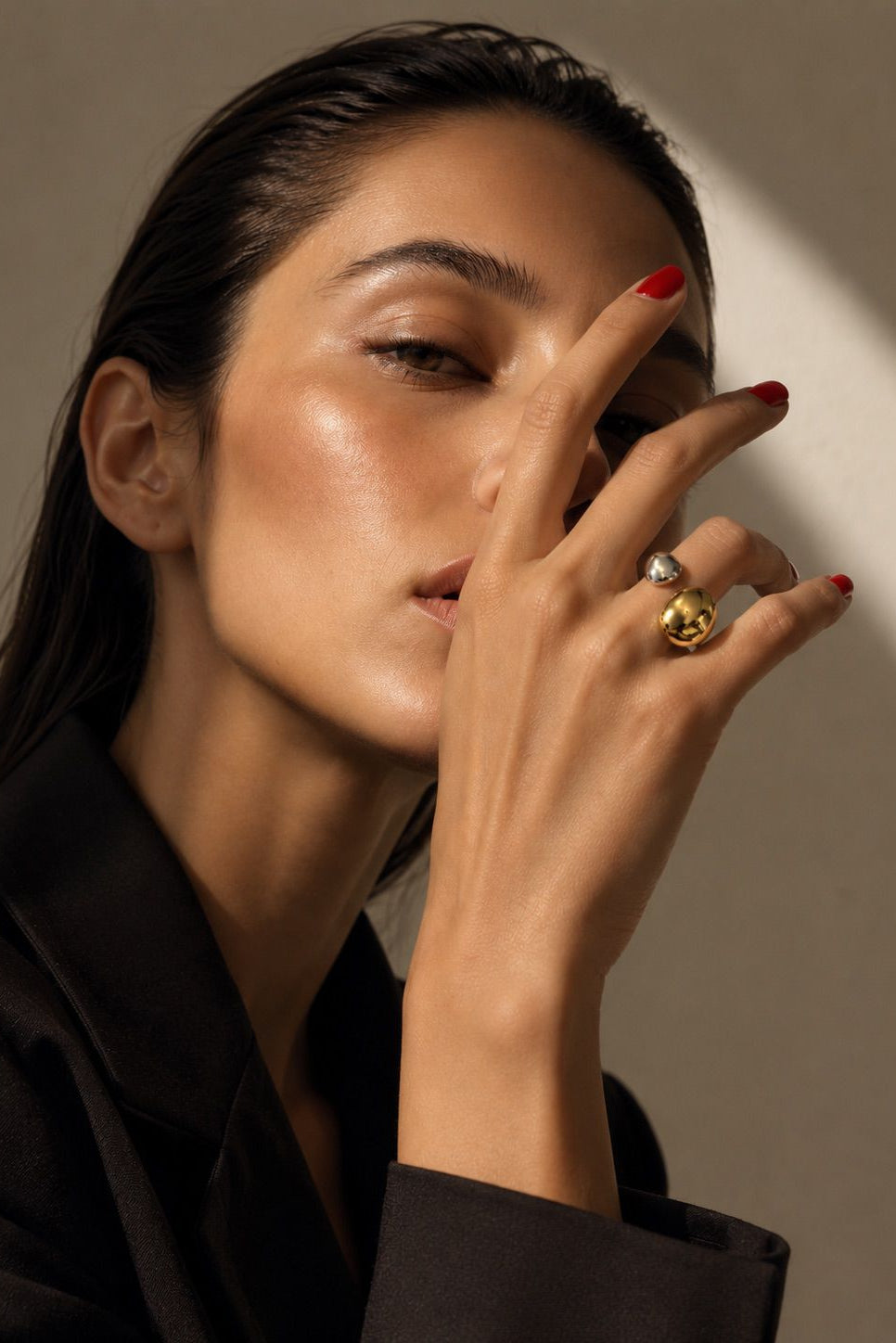 Woman with a gold ring on her finger against a neutral background