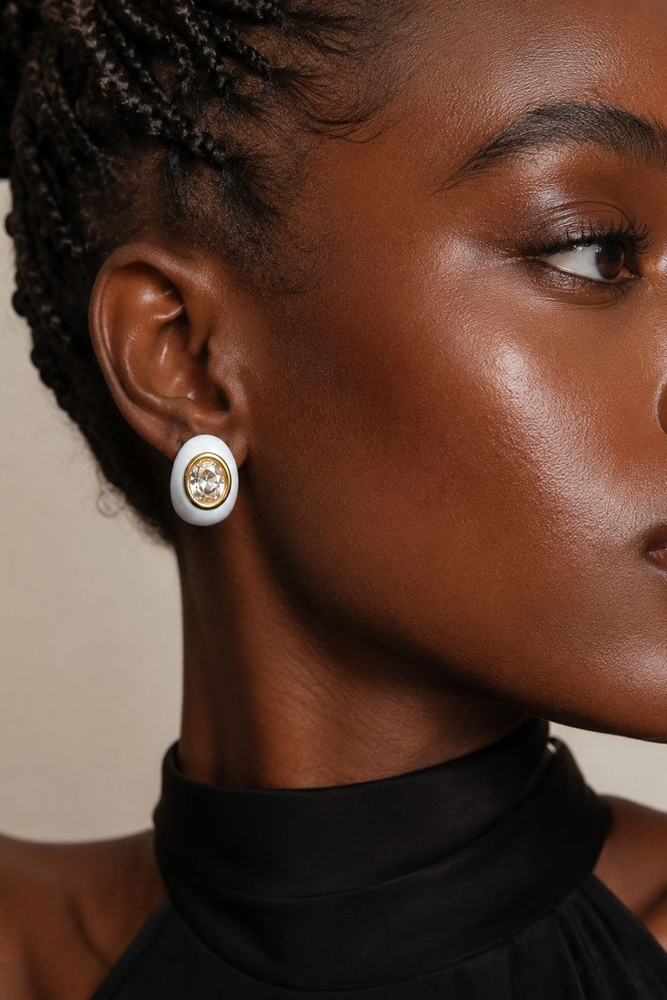 Close-up of a woman wearing a gold and white earring against a neutral background
