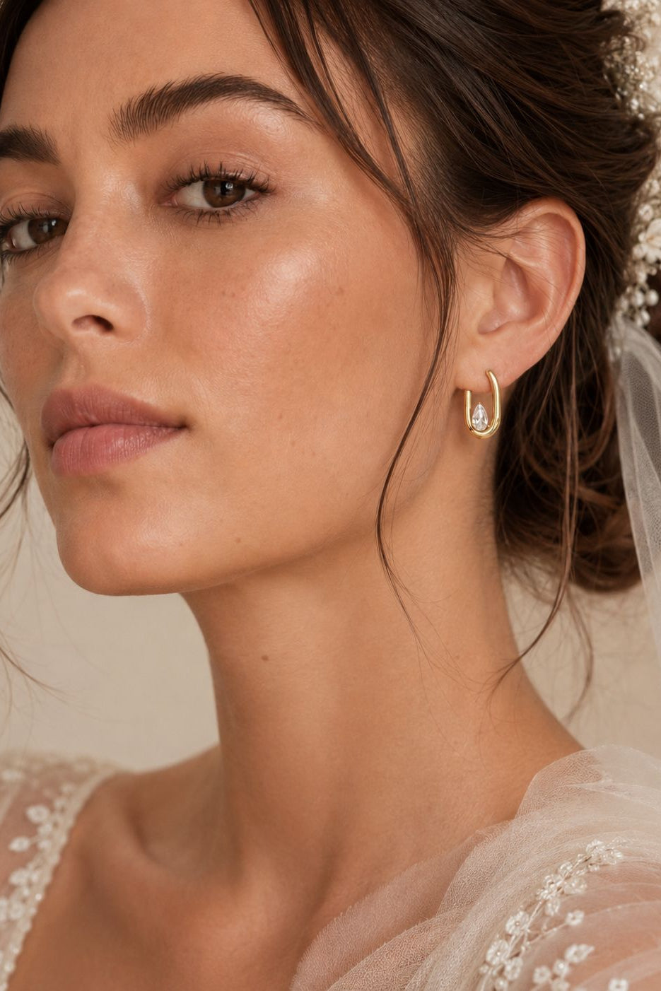 Close-up of a bride wearing a delicate earring with a soft focus on her face and veil.