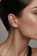 Close-up of a woman's ear wearing multiple zircons cuff against a neutral background