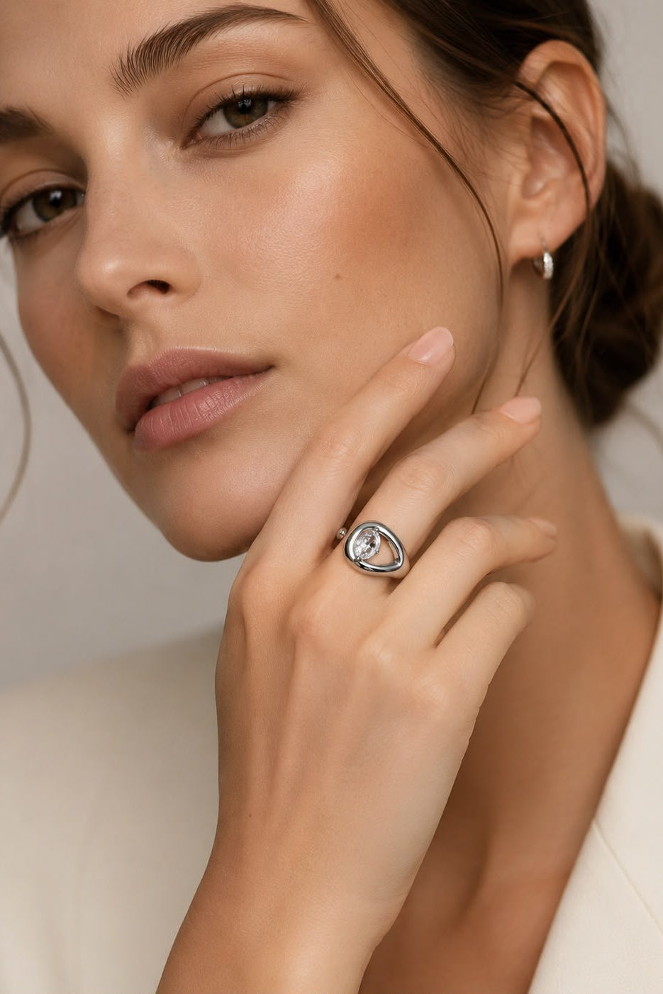 Woman wearing a ring with a clear gemstone on a neutral background