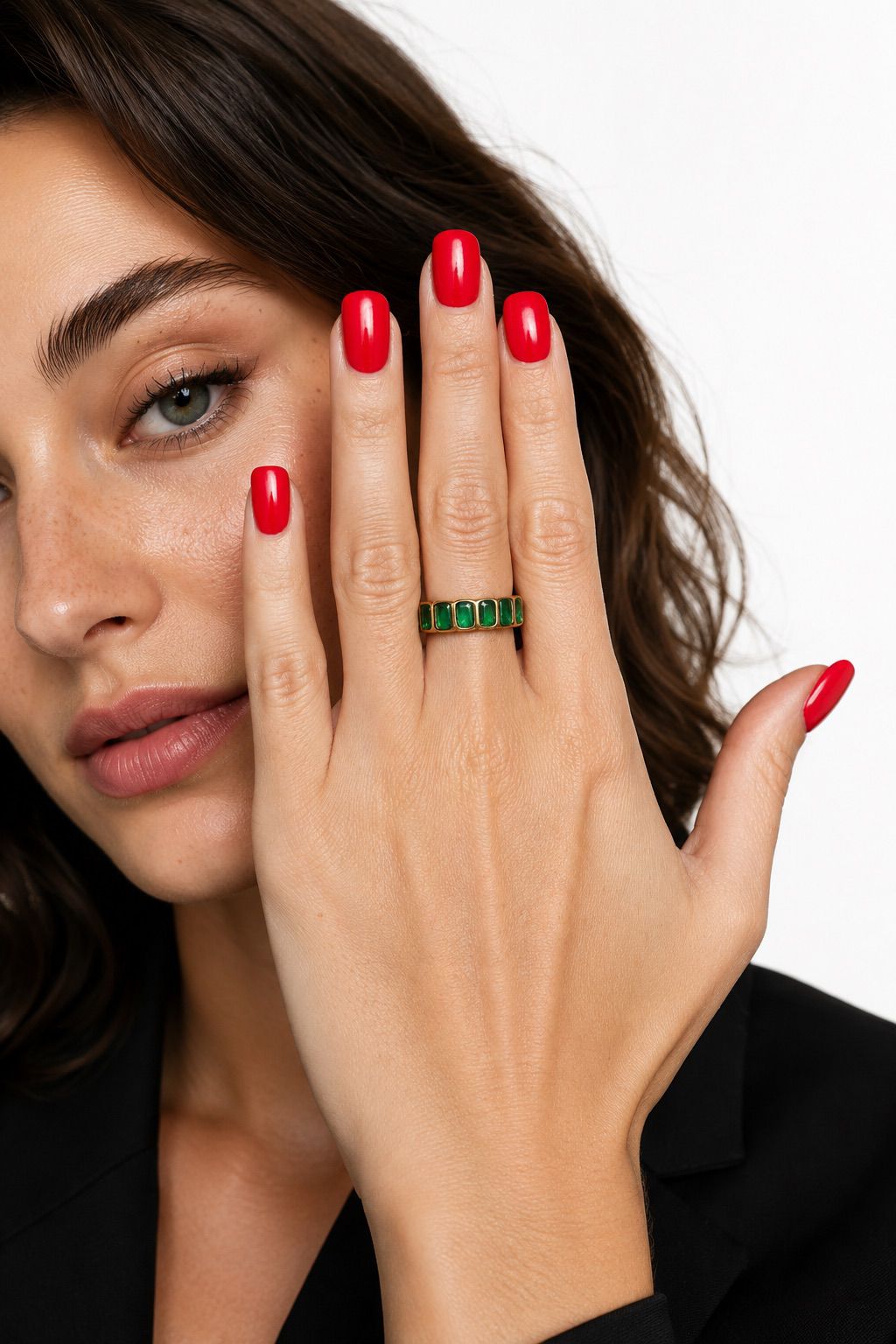 Woman with red nails and a green ring on her finger, wearing a black outfit.