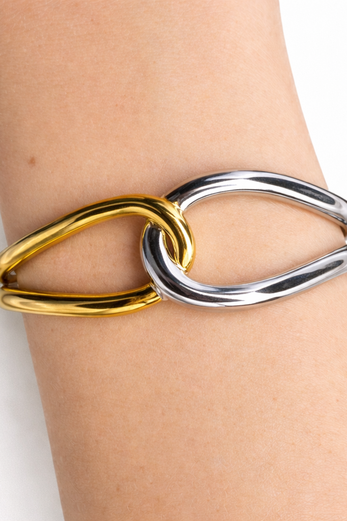Gold-plated and stainless steel chain-link bracelet on a wrist against a white background