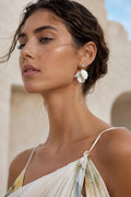 Woman wearing floral earrings with a neutral background
