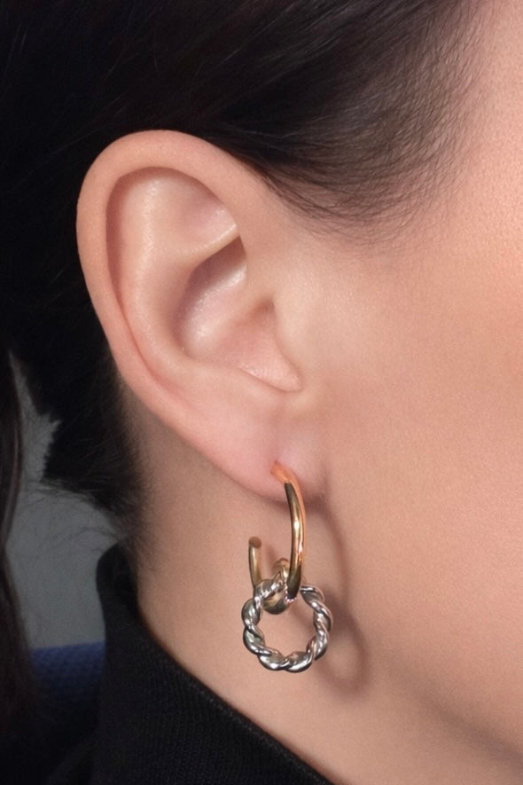 Close-up of an ear wearing a hoop earring with a dark background