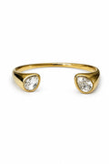 Gold wristlet with two clear gemstones on a white background