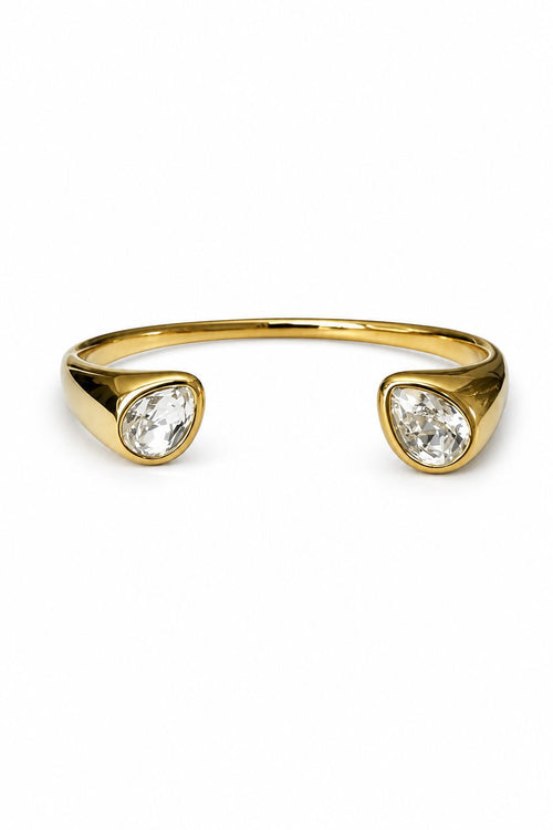 Gold wristlet with two clear gemstones on a white background