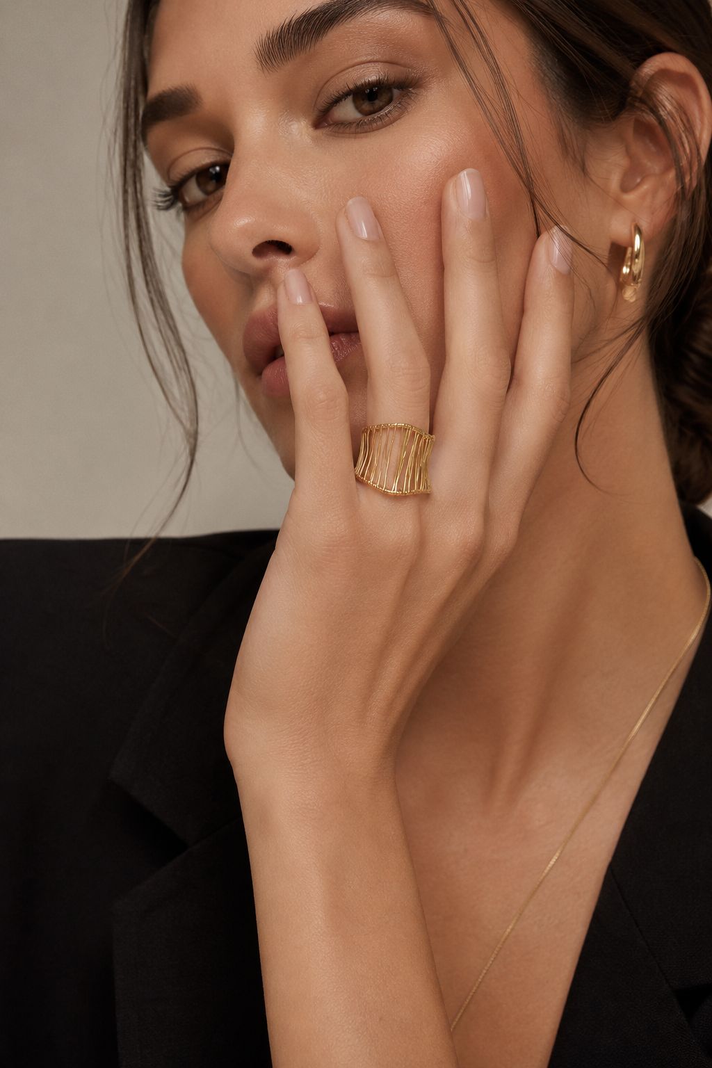Close-up of a woman's hand wearing a golden ring with a neutral background
